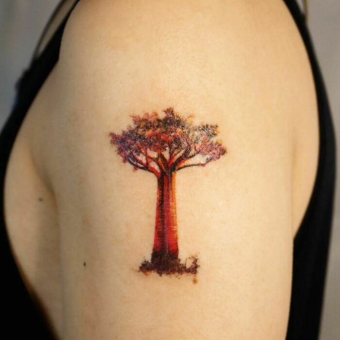 Majestic tree tattoo on upper arm with vibrant colors celebrating nature's wonders.