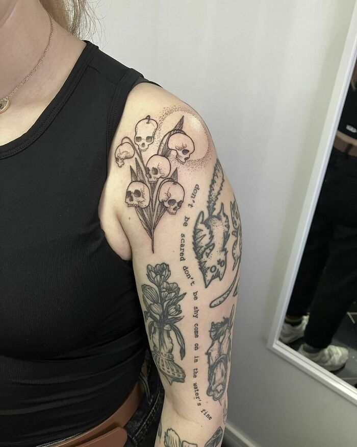 Arm adorned with detailed patchwork tattoos featuring skulls and flowers, displaying creative and unique design elements.