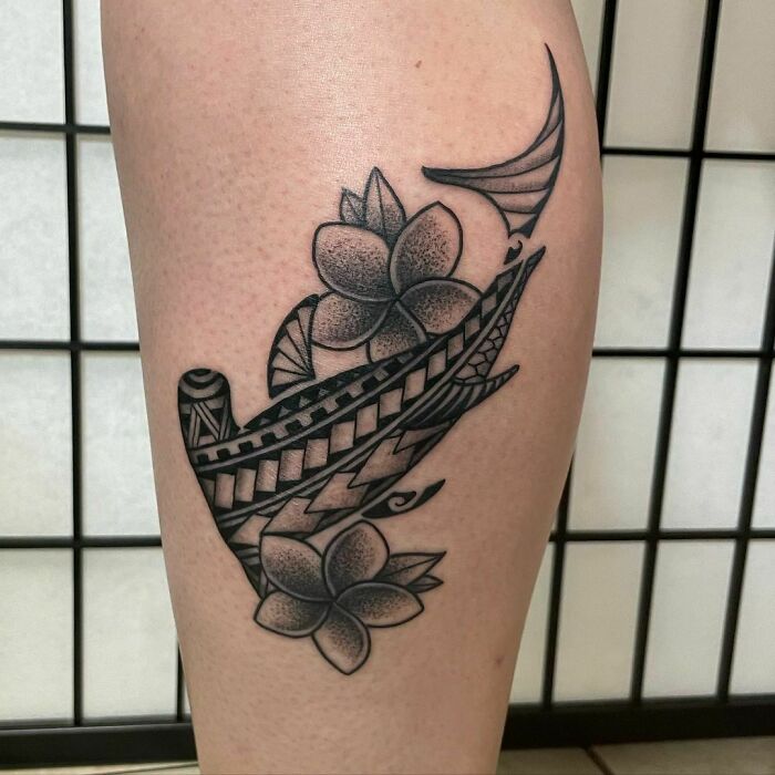 Tribal tattoo featuring geometric designs and floral elements on a leg against a tiled background.