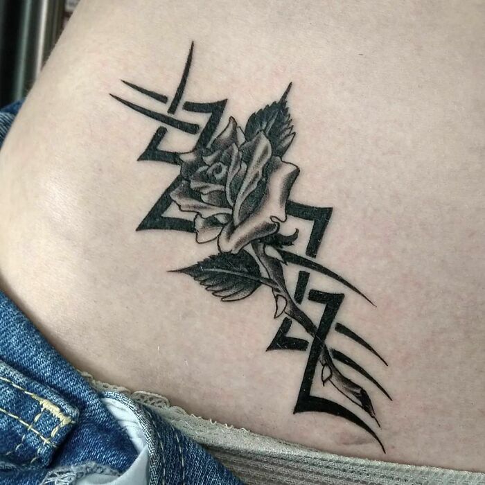 Tribal tattoo with a rose design on skin, featuring geometric patterns and detailed shading.