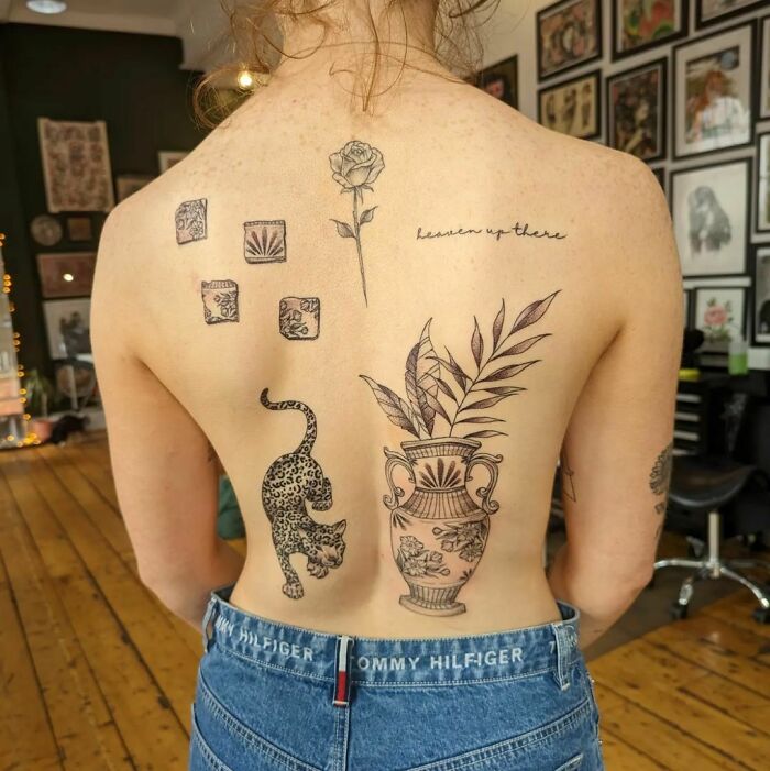 Person with diverse patchwork tattoos on their back, featuring a rose, vase, leopard, and more, in a tattoo studio.