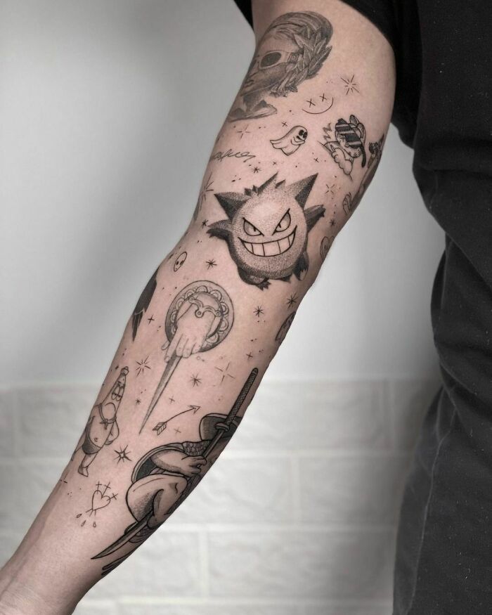 Tattooed forearm featuring diverse patchwork designs with cartoon characters and abstract symbols.