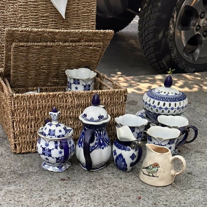 Wicker basket with vintage blue and white porcelain tea set discarded on NYC sidewalk, showing hidden treasures.