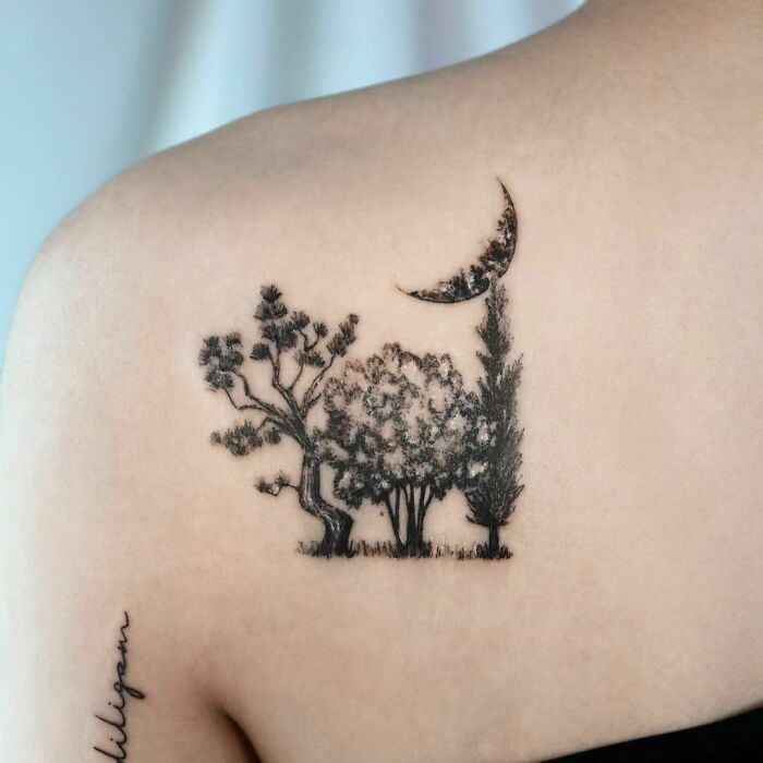 Tree tattoo with nature scene on shoulder, featuring a crescent moon and detailed trees, symbolizing the wonders of nature.