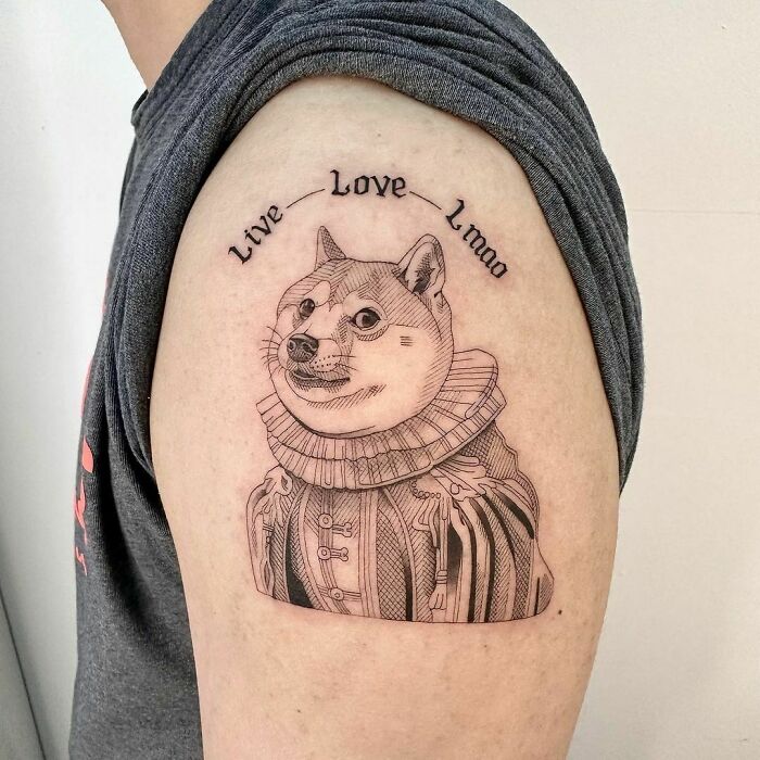 Pop culture tattoo of a Shiba Inu in historical attire with "Live Love Lmao" text on a person's upper arm.