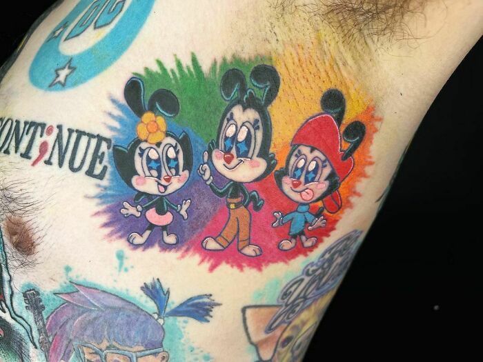 Colorful pop culture tattoos featuring cartoon characters on a person's skin.