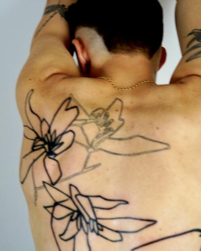 Tattoo artist's latest back piece featuring large floral outlines on a person's back.