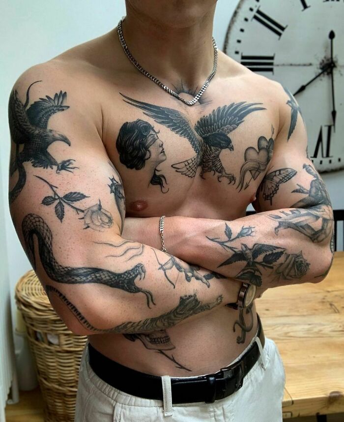 Man showcasing detailed patchwork tattoo design on chest and arms, featuring animals and floral elements.