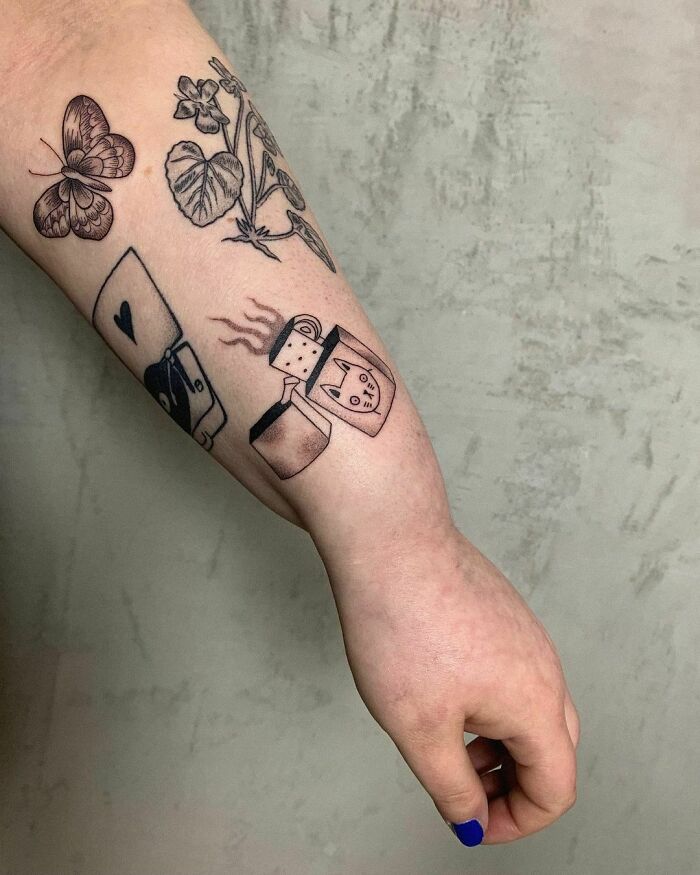 Arm showcasing creative patchwork tattoos, featuring a butterfly, plants, mug, and lighter, against a textured background.