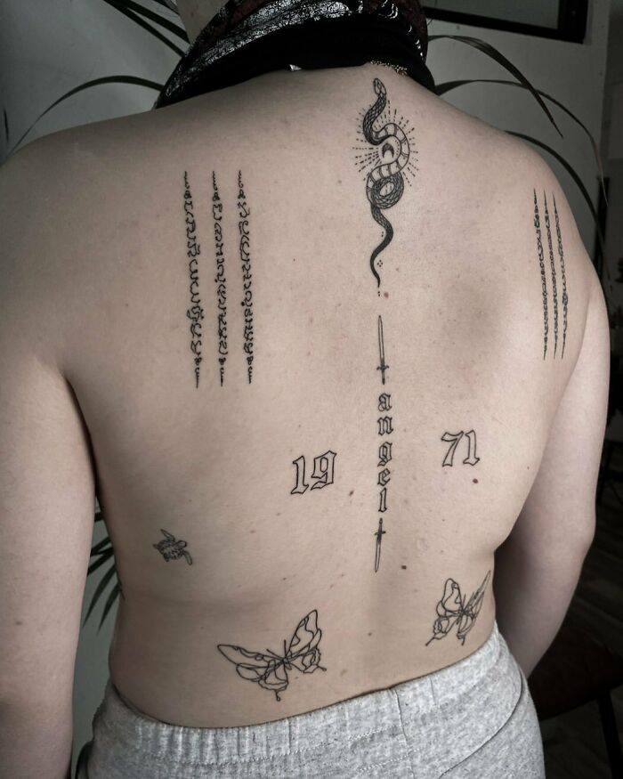 Back with patchwork tattoos, including a snake, numbers, and butterflies, showcasing modern tattoo art.