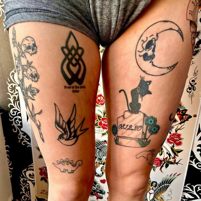 Close-up of patchwork tattoos on legs, featuring a cat, moon with skull, bird, and floral designs.