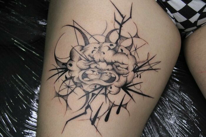 Tribal tattoo on leg featuring an intricate design with abstract elements.