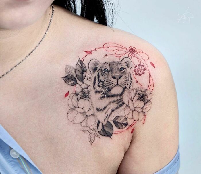 Tiger-themed collarbone tattoo with floral accents, showcasing stunning tattoo artistry for men and women.