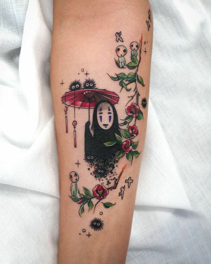 Pop culture tattoo featuring a faceless spirit with red umbrella, surrounded by forest spirits and flowers on a forearm.