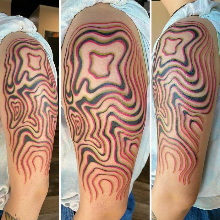 Colorful optical illusion tattoo design with wavy lines on an arm.