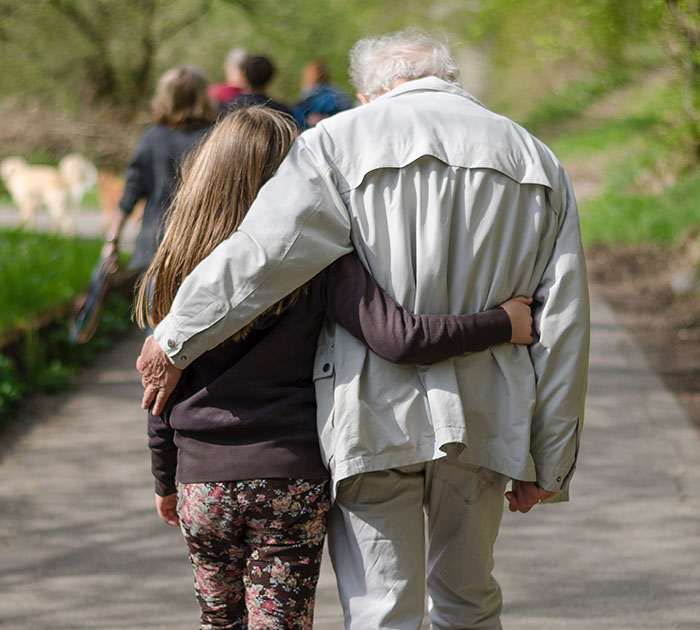 Grandpa and granddaughter walking closely on a park path, sharing moments of love and wise advice from grandparents.