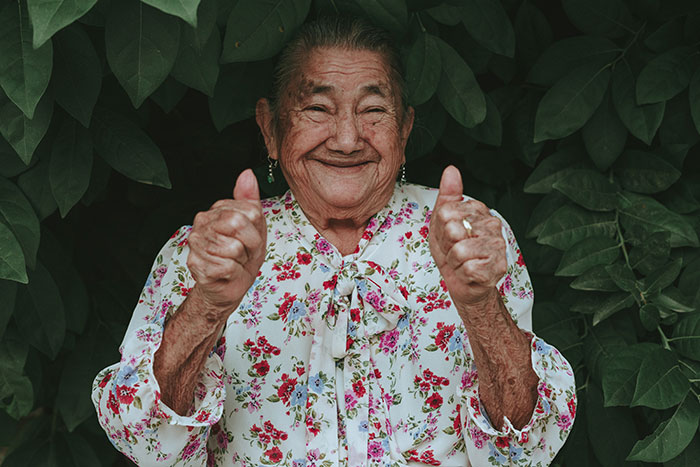 Grandma smiling and giving thumbs up, representing wise funny and naughty advice from grandparents with joy and warmth.