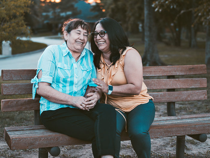 Mother and grandmother smiling together on a park bench, sharing moments inspired by grandparents' advice.