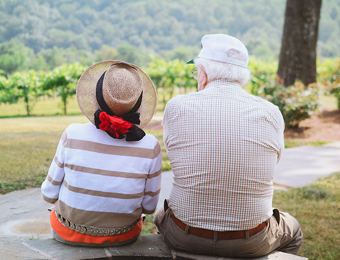 Elderly grandparents sitting outdoors, enjoying peaceful moment and sharing wisdom in a natural park setting.