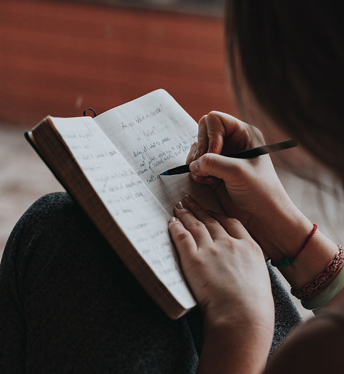 Woman writing in a notebook, capturing wise funny and naughty advice from grandparents for personal reflection.