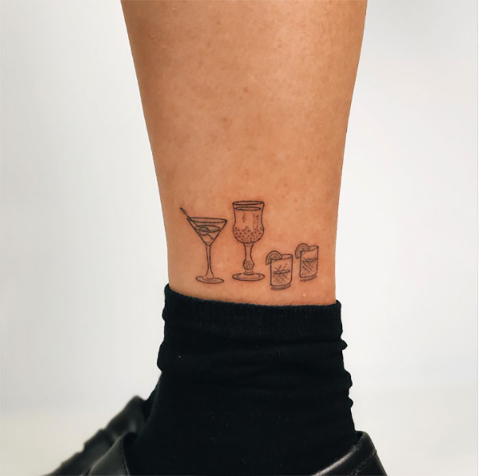 Ankle tattoo featuring four cocktail glasses above a black sock.