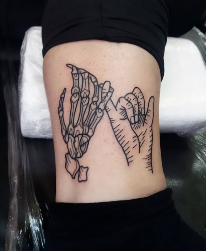 "Ankle tattoo design of a skeletal hand and human hand making a pinky promise."