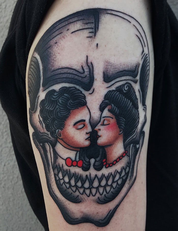 Optical illusion tattoo of a skull formed by a couple kissing, showcasing mind-bending design on arm.