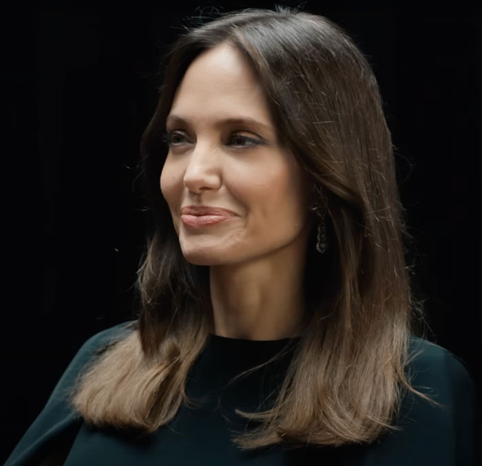 Angelina Jolie sitting and trying not to laugh 