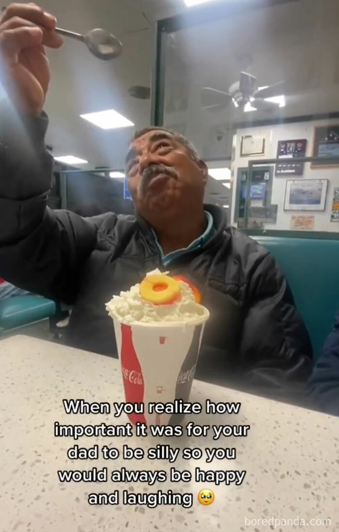 Man in diner being playful with a spoon, embodying classic dad moves, with a sundae on the table.