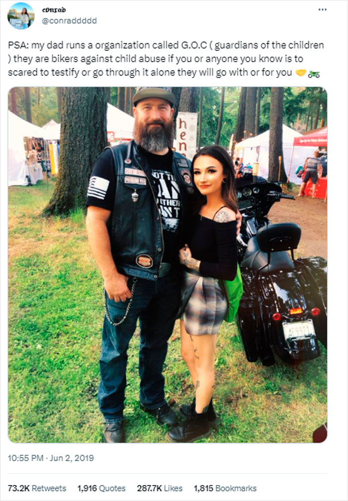 Biker dad posing with woman, promoting child protection group G.O.C. in park setting.