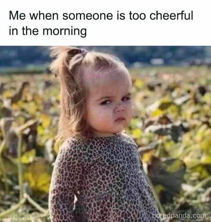 Grumpy child making a funny face in a field, expressing annoyance at morning cheerfulness.