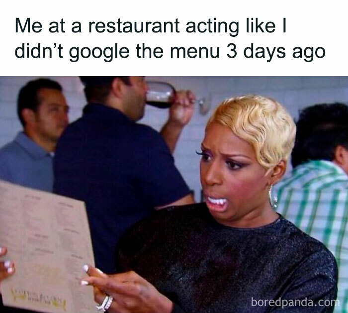 Woman humorously pretending to study a restaurant menu she already googled, capturing the essence of funny memes.