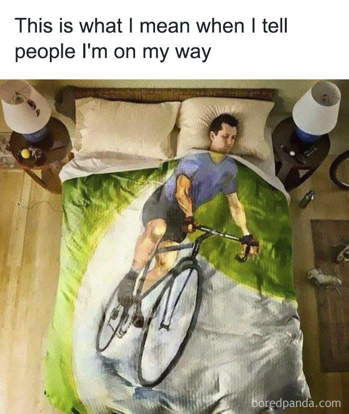 Person lying in bed with a blanket showing a cyclist, a relatable introvert meme about staying in but claiming to be on the way.