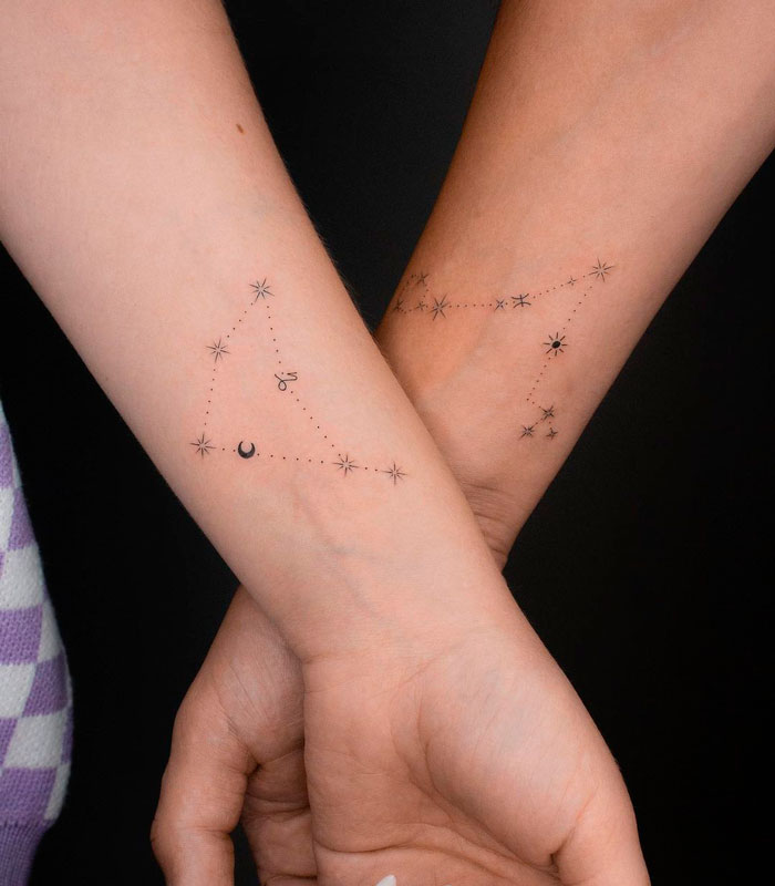 Matching tattoos on arms depicting star constellations for couples or friends, symbolizing connection and unity.