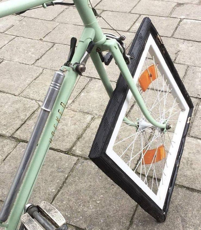 Cursed memes: Bicycle with a square wheel on a cobblestone path.