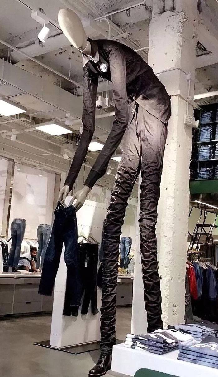 Cursed meme featuring Slenderman in a store, humorously holding a pair of jeans, blending eerie and comedic elements.