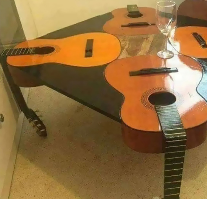 Cursed meme of a table made from guitars, featuring a glass on top.
