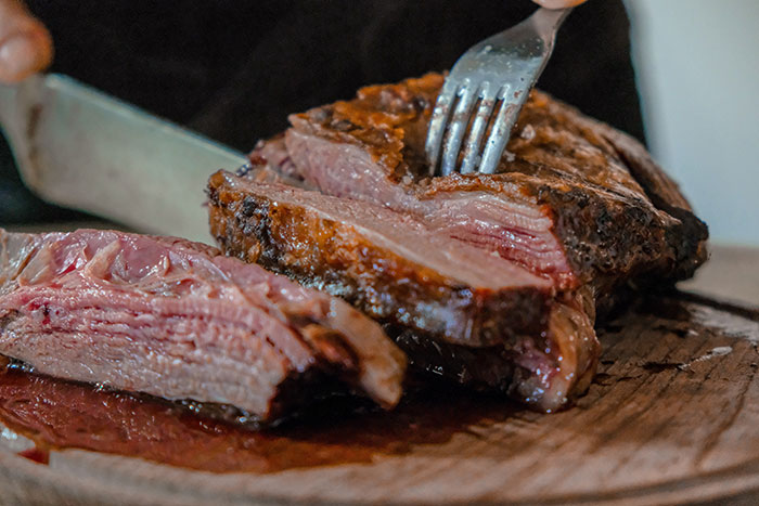 Slicing a juicy steak, illustrating a food history fact about meat preparation.