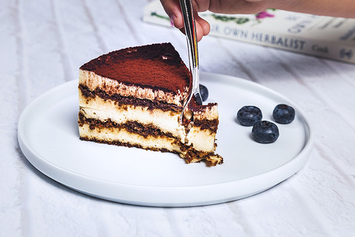 A slice of tiramisu cake with a fork, representing the rich food history behind classic desserts.