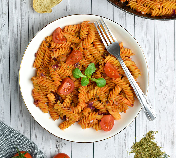 A plate of pasta with tomatoes and herbs, illustrating the rich food history facts of Italian cuisine.