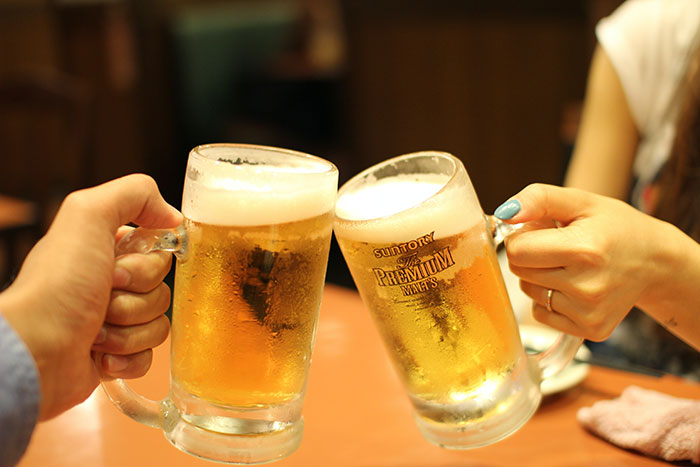 Two people toasting with beer mugs, celebrating food history facts about beverages.