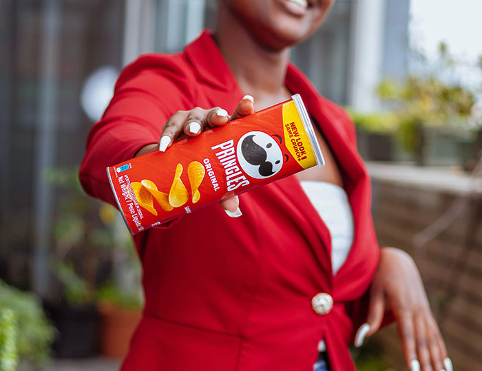 A person holding a can of Pringles chips. Learn about the surprising food history facts behind popular snacks.
