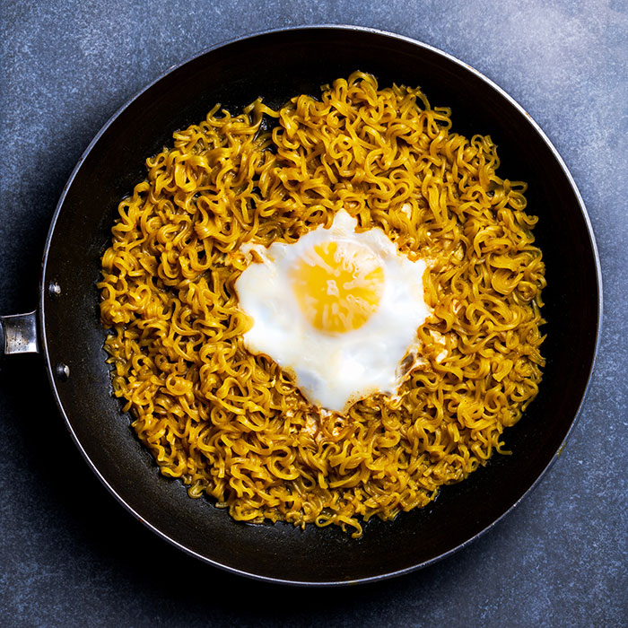 Fried egg on a bed of noodles in a pan, evoking intriguing food history facts about global cuisine.