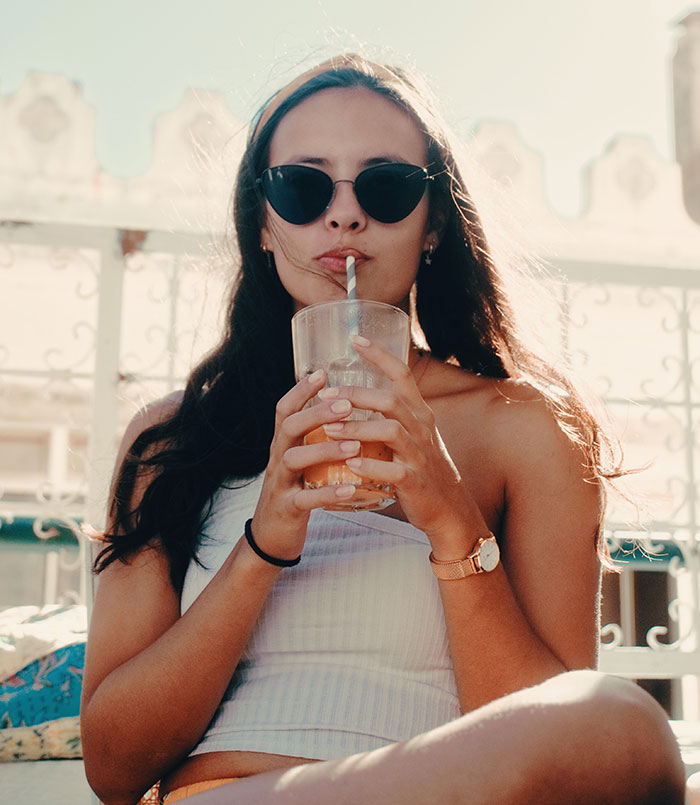 Woman in sunglasses sipping a drink, representing captivating food history facts and culinary stories.