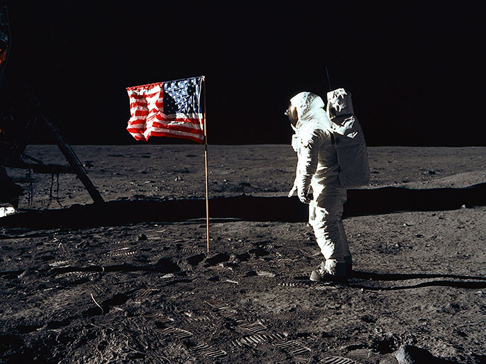 Astronaut on the moon with an American flag, relating to food history facts about space food.