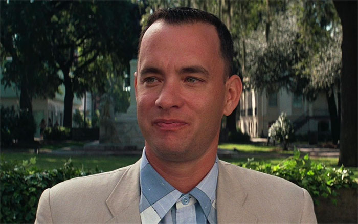 Forrest Gump wearing a beige suit outdoors, capturing iconic Forrest Gump quotes in a classic movie scene.