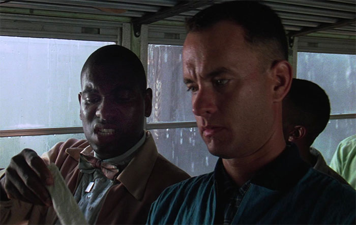 Forrest Gump wearing a raincoat, sitting on a bus during rain, capturing a memorable moment from Forrest Gump quotes.
