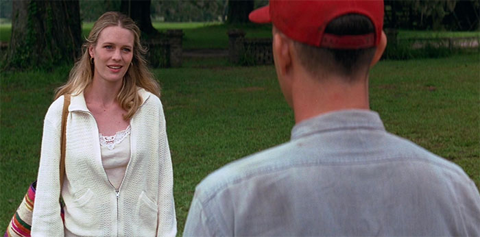 Jenny and Forrest Gump talking outdoors in a grassy area, capturing a moment from Forrest Gump quotes collection.
