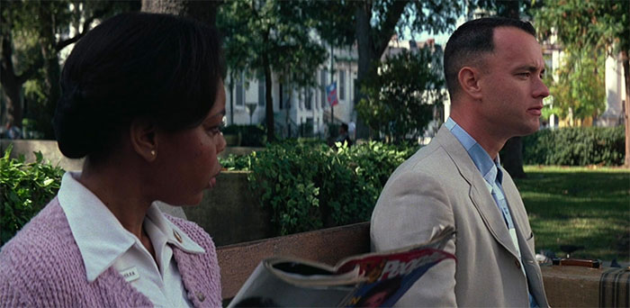 Forrest Gump sitting on a bench talking with a woman in a park scene illustrating Forrest Gump quotes