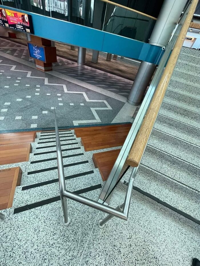 Two Levels Of Stairs In What Looks To Be A Highly Trafficked Area, Where The Center Railing Connects To The Left Side Of The Second Set Of Stairs. Thus Completely Blocking Off Entry From The Left Side Of The Stairs